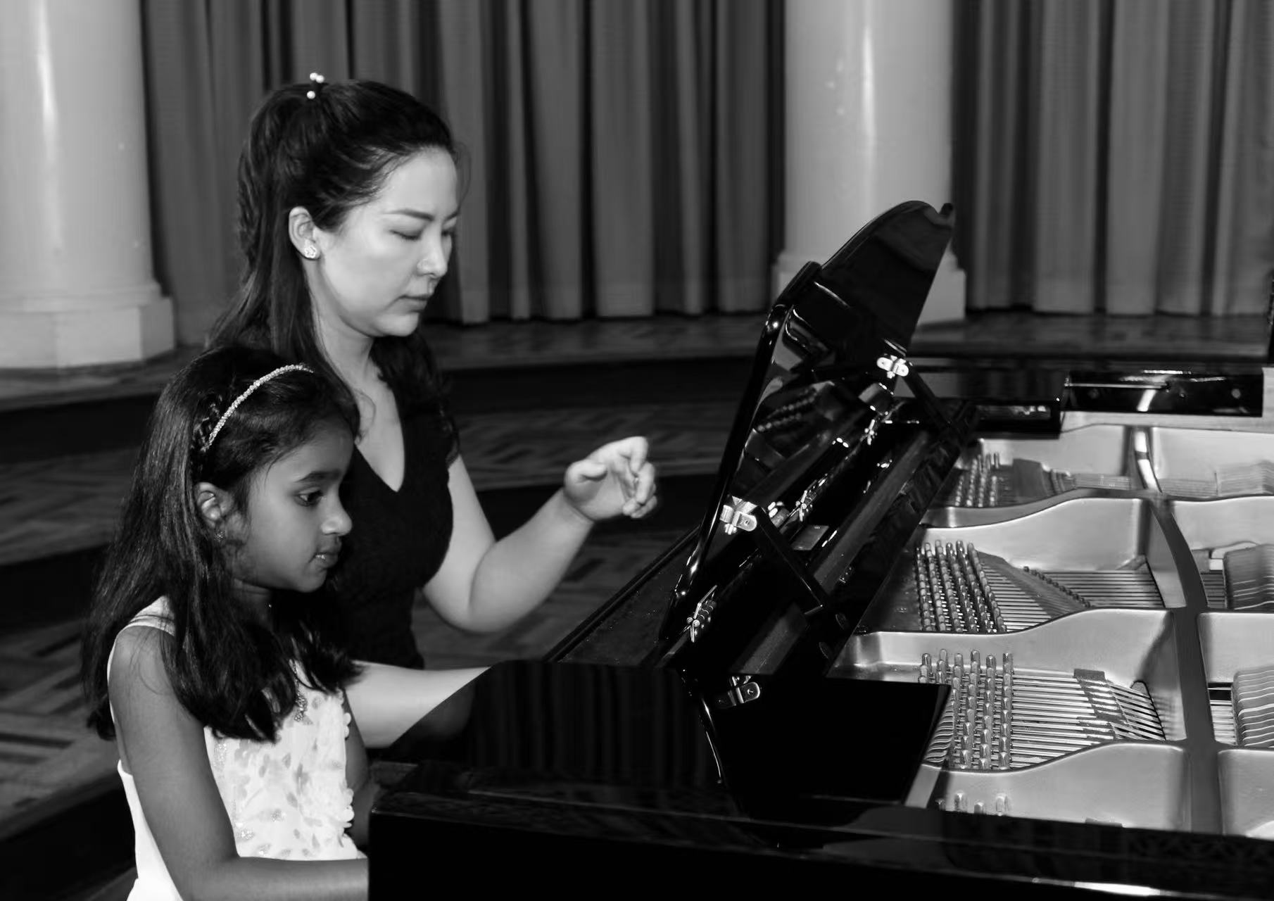 Jin Du guiding a young piano student at a grand piano