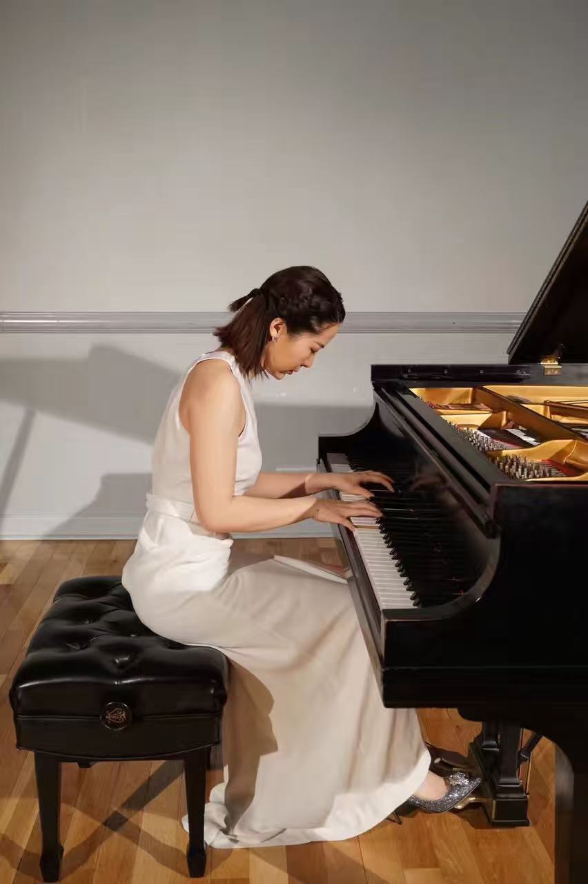 Jin Du performing at the keyboard in a white concert gown